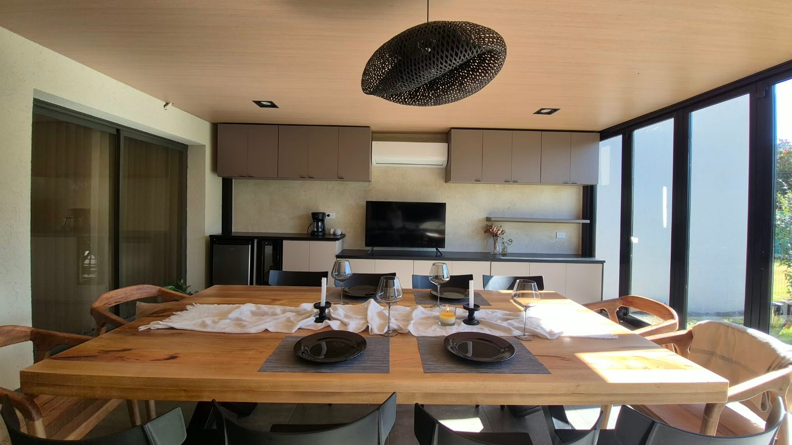 Comedor semi-exterior moderno con mesa de madera y lámpara tejida — proyecto OBRA JJ, por Cc Arquitectura & Diseño, en Colectora Au RN 20 km14